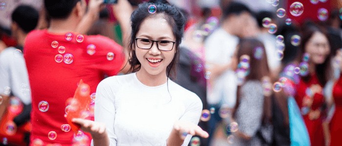 Photo of a woman wearing eyeglasses and white shirt enjoying bubbles