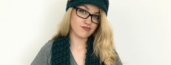 Photo of a blonde woman wearing a crocheted hat and scarf on top of a gray shirt