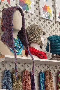 Increase Craft Fair Profits - image of a craft fair booth with a display of several crochet hats and scarves hanging below