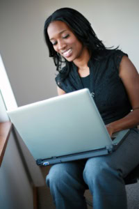 Email List - image of a woman smiling, working on a laptop that's sitting on her knees