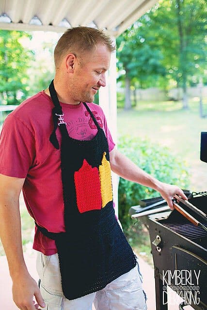 Photo of a guy grilling outdoors wearing the crocheted BBQ toolbelt apron