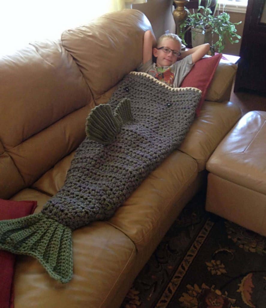 Photo of a boy with eyeglasses lying on a leather sofa using the Large Mouth Bass Blanket