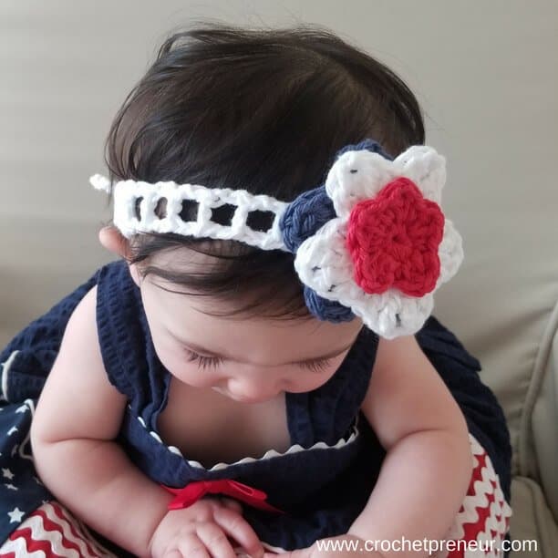 Photo of a baby wearing the white Summer Headband with blue, white, and red flower detail