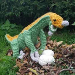 Photo of a crocheted mommy Therizinosaurus dinosaur protecting her eggs