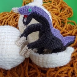 Photo of the crocheted baby Therizinosaurus dinosaur getting out of its shell
