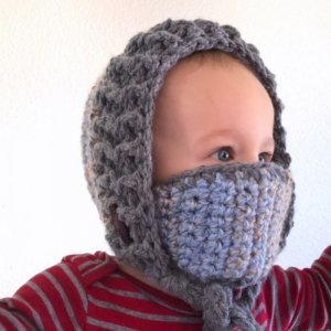 A baby wearing the Snow Day Hood winter hat with its detachable mask