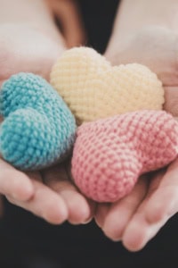crochet designer free things - image of a pair of hands, holding 3 small amigurumi hearts