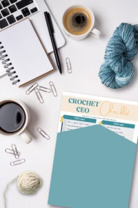 crochet business productivity - image of a busy workspace with office supplies, yarn and hook, and a copy of the free Crochet CEO Checklist