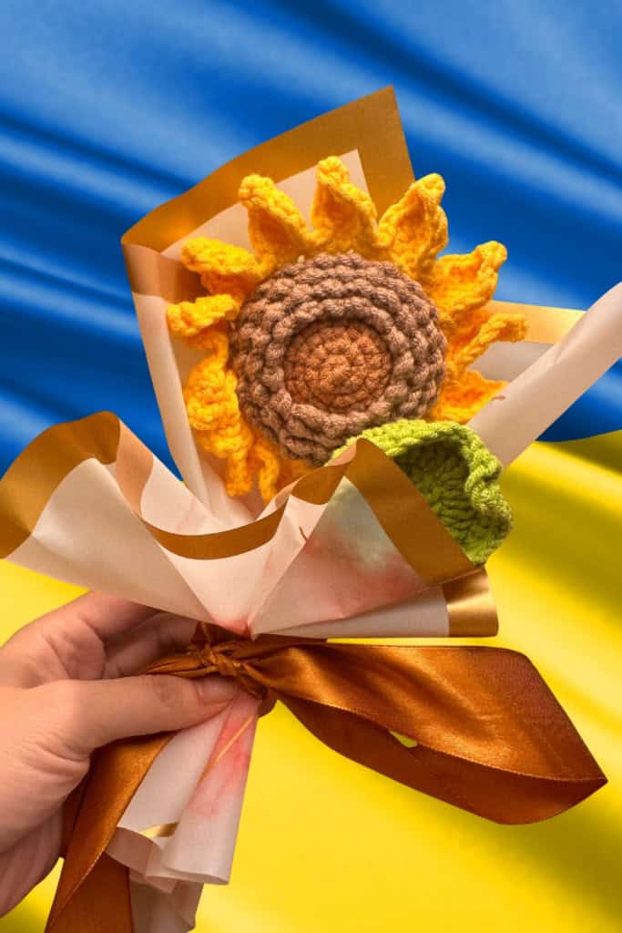 makers in Ukraine - image of a crocheted sunflower with the Ukrainian flag in the background