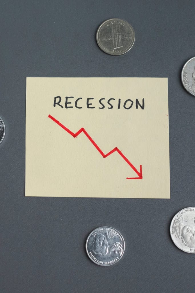 handmade business survive recession - image of a sticky note that read "recession," with a red arrow trending down. it's surrounded by several coins
