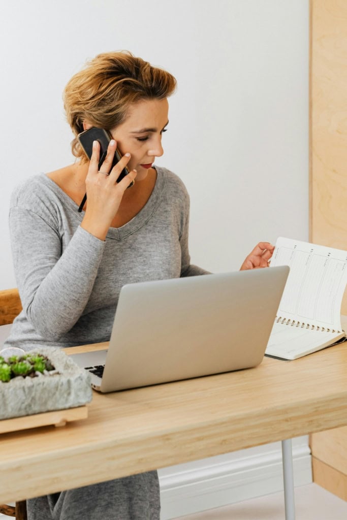 handmade business strategy recession p woman working at a desk in a light, bright office, with a laptop in front of her, talking on the phone