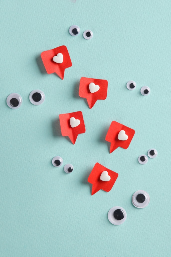 market crochet business - several red paper speech bubbles with white hearts. They're surrounded by several pairs of googly eyes