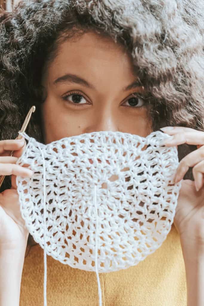 How to Make Money from Crochet Without Losing Your Passion - image of a woman peeking over a crochet circle, with happy eyes