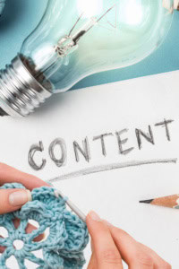 Crochet Business Content Ideas - image of a piece of paper, with "content" written in pencil, with a light bulb and a pair of hands crocheting a flower
