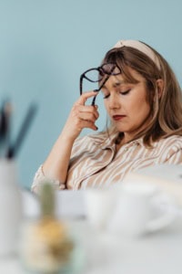 Avoiding Crochet Business Burnout - Image of a woman seated at an office workspace, with eyes down and a discouraged expression