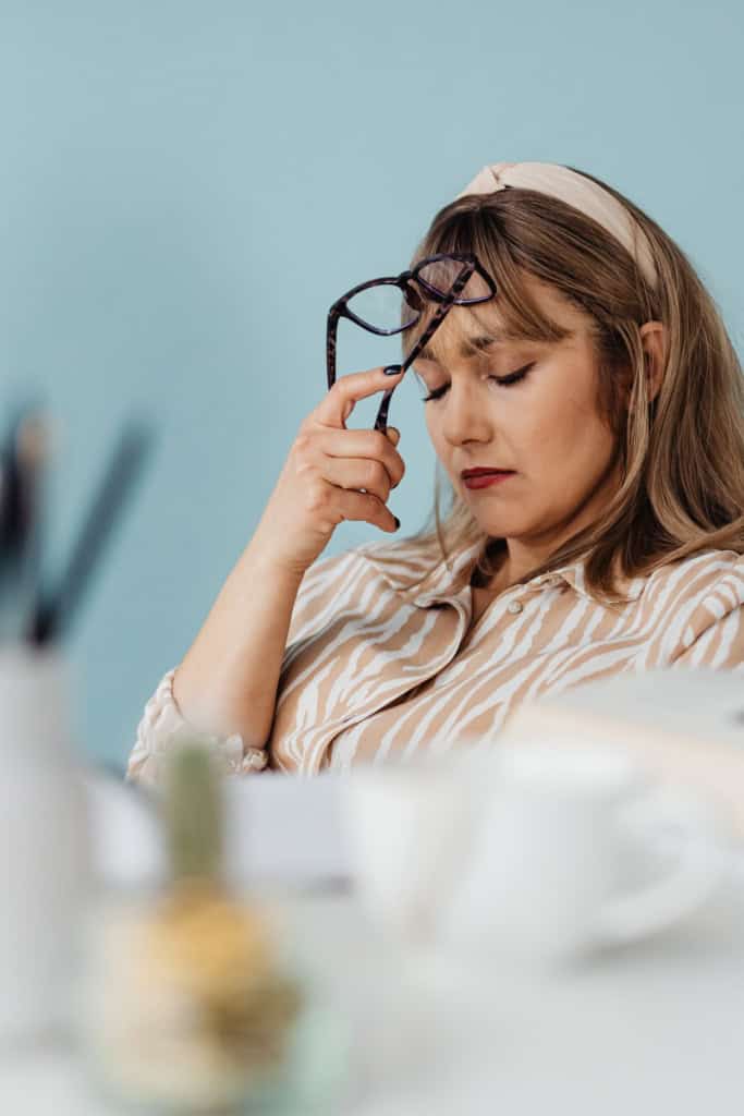 Avoiding Crochet Business Burnout - Image of a woman seated at an office workspace, with eyes down and a discouraged expression