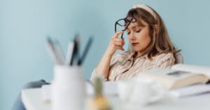 Avoiding Crochet Business Burnout - Image of a woman seated at an office workspace, with eyes down and a discouraged expression