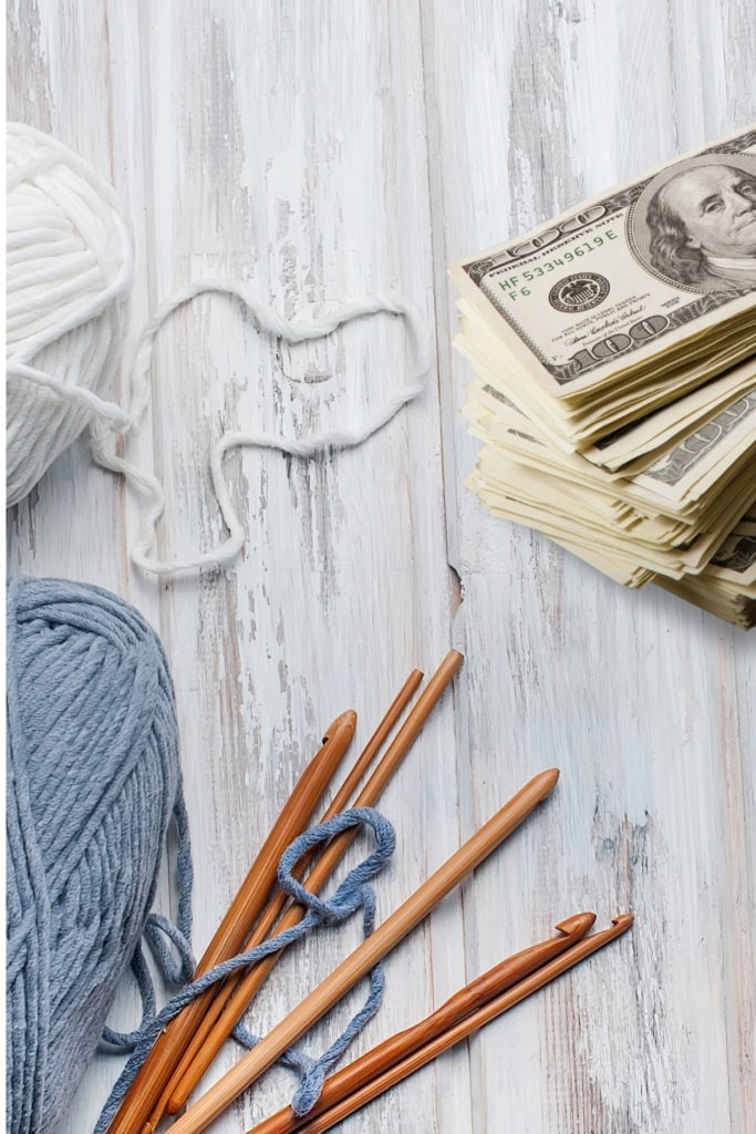 Image of yarn balls, crochet hooks, and a stack of money