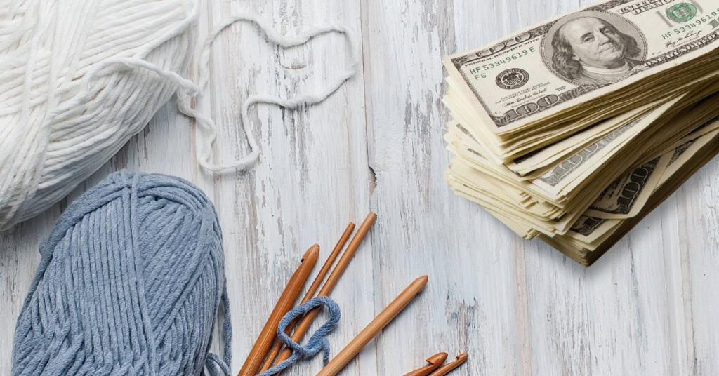 Image of yarn balls, crochet hooks, and a stack of money