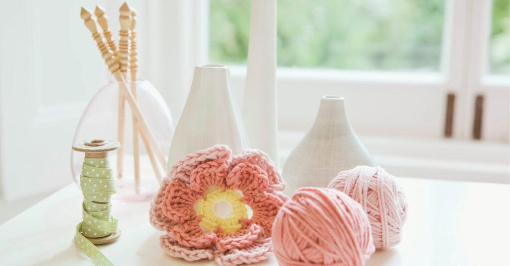 Crochet Craft Fair Ideas for Spring - image of decorative vases, one full of crochet hooks, a large crochet flower, and a ball of yarn