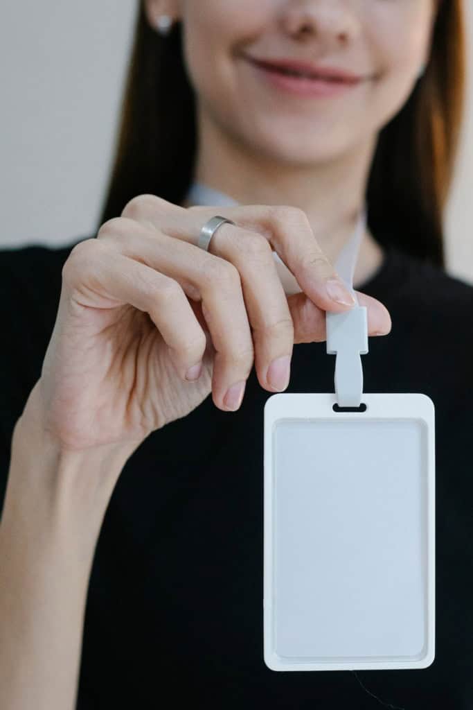 How to Choose a Name for your Crochet Business - Shows a woman holding up a blank name tag on a lanyard