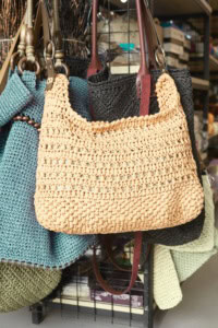 An assortment of crochet bags, hanging on a display rack