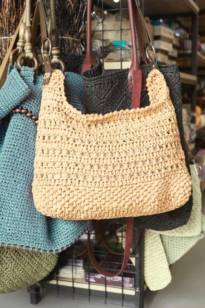 An assortment of crochet bags, hanging on a display rack