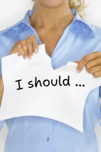 Image of a woman tearing a piece of paper with her hands, on which is written "I should ..."